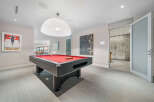 Experience ultimate entertainment in this modern game room, featuring a sleek pool table with a vibrant red felt.