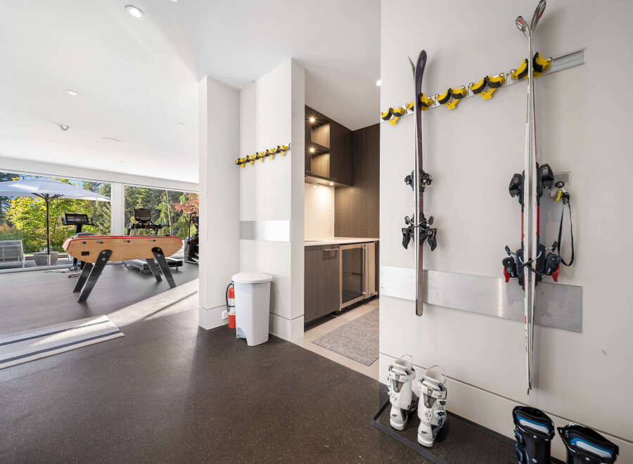 This modern home features a dedicated ski storage area with wall-mounted racks and boot trays, perfect for outdoor enthusiasts.