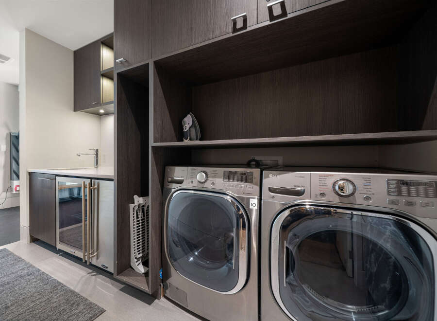Discover modern convenience in this laundry room, featuring a sleek dark wood cabinetry system.