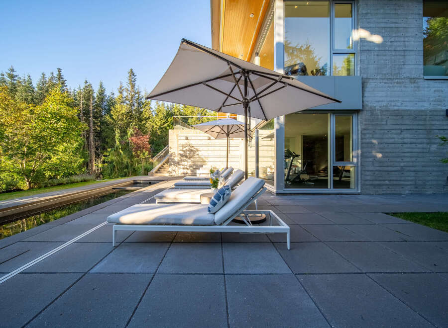 Experience luxurious outdoor living with this modern patio featuring comfortable lounge chairs and large umbrellas for shade.