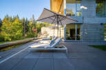 Experience luxurious outdoor living with this modern patio featuring comfortable lounge chairs and large umbrellas for shade.