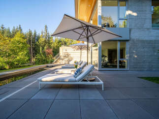 Experience luxurious outdoor living with this modern patio featuring comfortable lounge chairs and large umbrellas for shade.