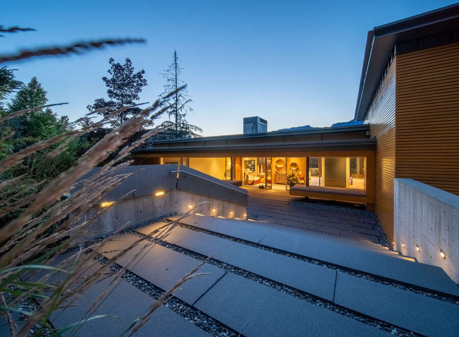 Experience modern luxury in this stunning home, featuring a sleek concrete and wood exterior.
