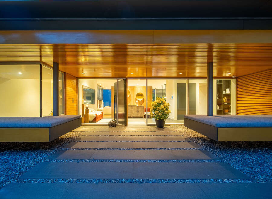 Experience modern luxury with this stunning entryway featuring sleek wooden accents and expansive glass doors that open into a beautifully furnished living space.