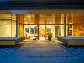 Experience modern luxury with this stunning entryway featuring sleek wooden accents and expansive glass doors that open into a beautifully furnished living space.