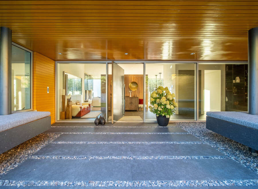 Step into modern luxury with this stunning entryway featuring sleek wooden ceilings and a vibrant orange accent wall.