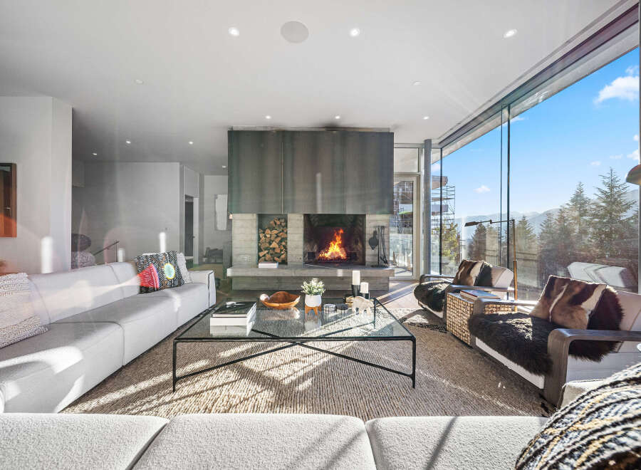 Experience luxury mountain living in this stunning contemporary home, featuring a grand fireplace as the centerpiece of the living room.