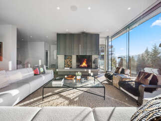 Experience luxury mountain living in this stunning contemporary home, featuring a grand fireplace as the centerpiece of the living room.