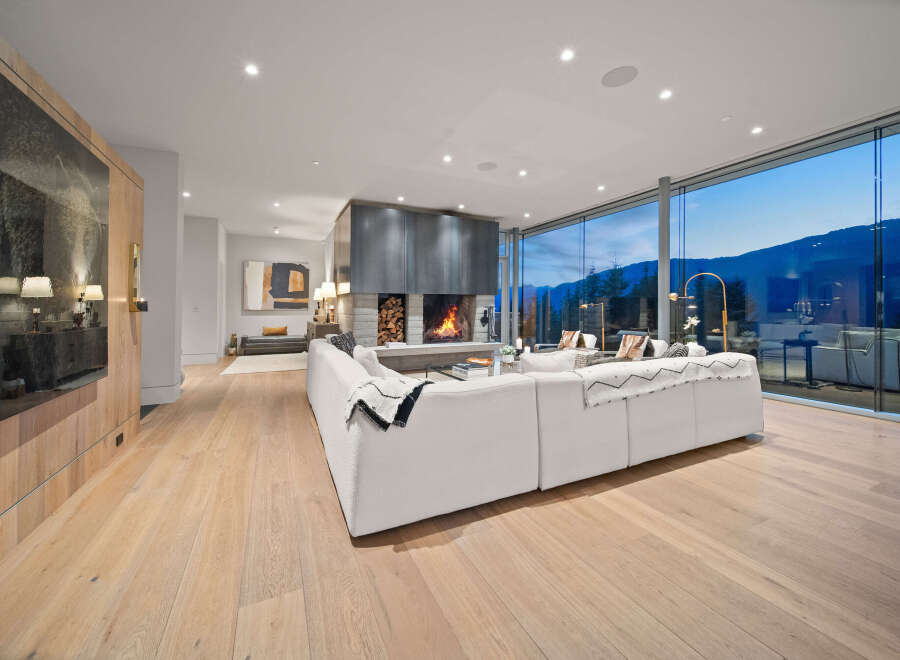 Experience luxury living in this stunning modern home featuring a grand fireplace and expansive floor-to-ceiling windows that offer breathtaking mountain views.