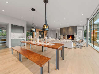 Experience modern luxury in this open-concept living space, featuring a sleek dining area with a long wooden table and benches, perfect for gatherings.