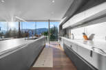 Experience modern luxury in this stunning kitchen featuring sleek grey cabinetry and expansive windows that frame breathtaking mountain and forest views.