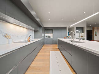 Experience modern luxury in this sleek, gray gourmet kitchen, featuring a stunning marble backsplash and a spacious island with a double sink.