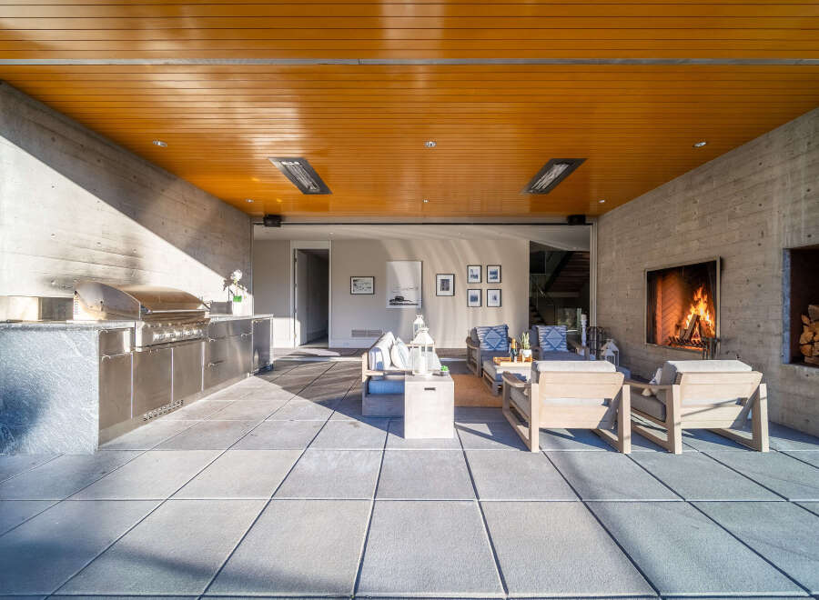 Experience luxurious outdoor living with this stunning patio featuring a built-in stainless steel grill, a cozy fireplace, and comfortable seating.
