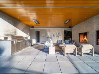 Experience luxurious outdoor living with this stunning patio featuring a built-in stainless steel grill, a cozy fireplace, and comfortable seating.