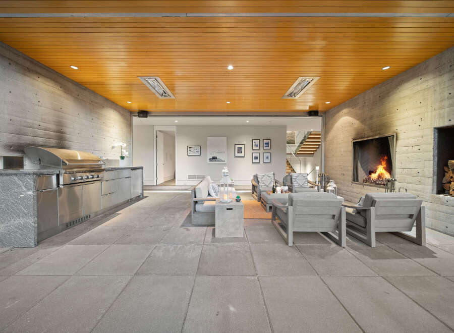 Experience seamless indoor-outdoor living with this stunning covered patio, featuring a built-in grill station and a cozy fireplace.