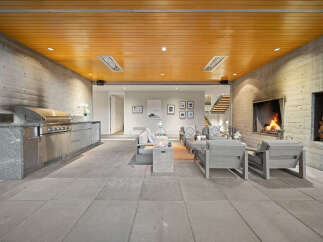 Experience seamless indoor-outdoor living with this stunning covered patio, featuring a built-in grill station and a cozy fireplace.
