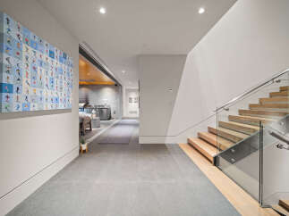 Experience modern luxury in this stunning home featuring a sleek staircase with glass railings and warm wood treads.