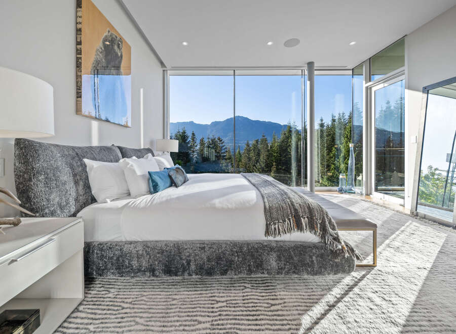 Experience breathtaking mountain views from this luxurious master bedroom, featuring expansive floor-to-ceiling windows that flood the space with natural light.