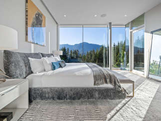 Experience breathtaking mountain views from this luxurious master bedroom, featuring expansive floor-to-ceiling windows that flood the space with natural light.
