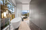 Experience luxury living with this stunning master bathroom featuring a freestanding bathtub and expansive windows offering breathtaking mountain and forest views.