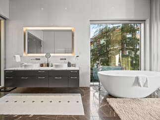 Experience modern luxury in this stunning bathroom featuring a freestanding soaking tub with a sleek chrome faucet and a spacious double vanity with vessel sinks.