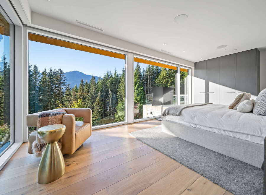 Experience breathtaking mountain views from this luxurious bedroom, featuring expansive floor-to-ceiling windows that flood the space with natural light.