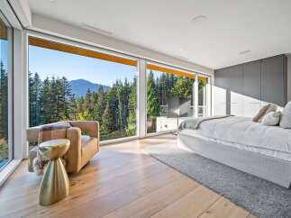 Experience breathtaking mountain views from this luxurious bedroom, featuring expansive floor-to-ceiling windows that flood the space with natural light.