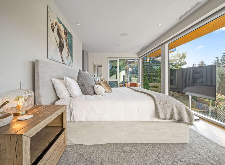 Experience luxury living in this stunning bedroom featuring a king-sized bed with plush linens and a cozy throw blanket.