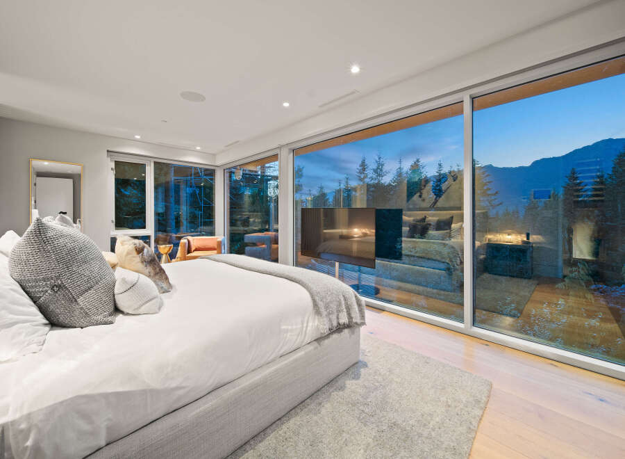Experience luxurious mountain living in this stunning bedroom featuring a king-sized bed with plush pillows and a cozy throw blanket.