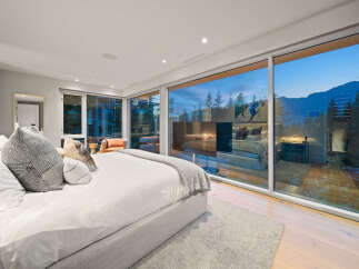 Experience luxurious mountain living in this stunning bedroom featuring a king-sized bed with plush pillows and a cozy throw blanket.