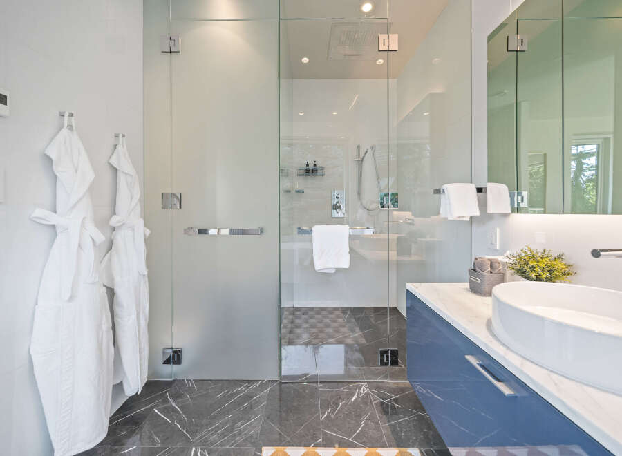 Experience modern luxury in this stunning bathroom featuring a spacious glass-enclosed shower with a rainfall showerhead.
