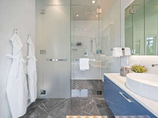 Experience modern luxury in this stunning bathroom featuring a spacious glass-enclosed shower with a rainfall showerhead.
