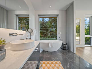 Experience luxury in this stunning modern bathroom featuring a freestanding soaking tub with a breathtaking view of the lush greenery outside.
