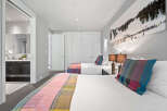Experience comfort and style in this inviting bedroom featuring two plush beds, perfect for families or groups.