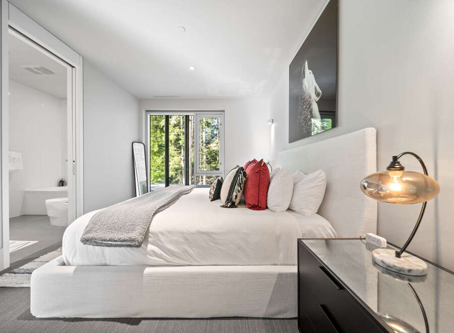 Experience modern luxury in this serene bedroom featuring a plush king-sized bed adorned with decorative pillows and a cozy throw.