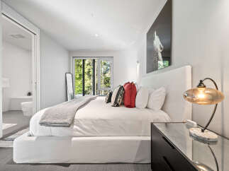 Experience modern luxury in this serene bedroom featuring a plush king-sized bed adorned with decorative pillows and a cozy throw.