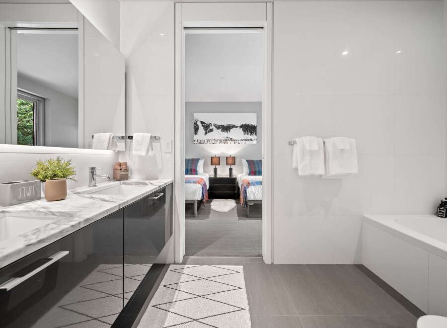 Experience modern luxury in this stunning bathroom featuring a sleek vanity with marble countertops and a deep soaking tub.
