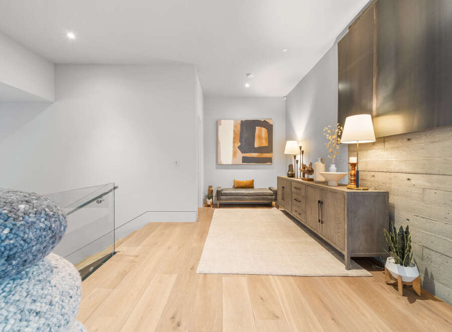 This modern hallway features a sleek gray leather bench with a mustard accent pillow, complemented by a large abstract artwork.