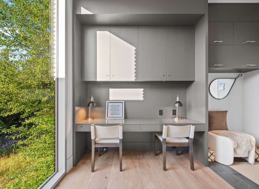 This modern home office features a sleek grey built-in desk with two matching chairs, perfect for a shared workspace or a couple.