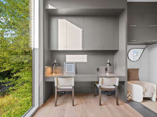 This modern home office features a sleek grey built-in desk with two matching chairs, perfect for a shared workspace or a couple.
