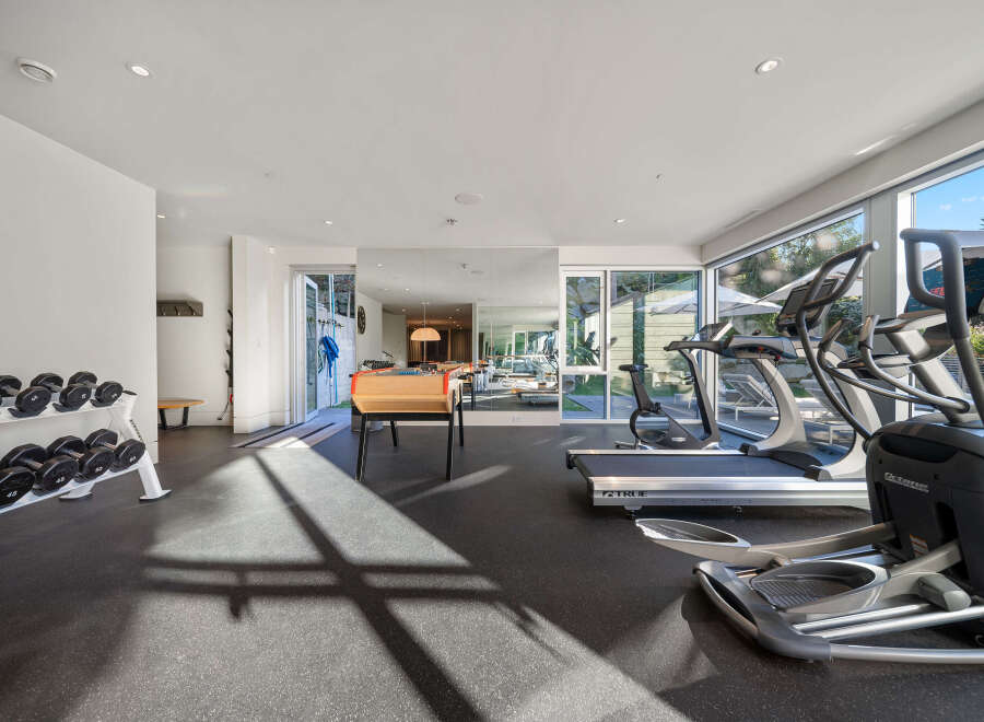 Elevate your fitness routine in this well-equipped home gym, featuring a full set of dumbbells, treadmills, and an elliptical machine.