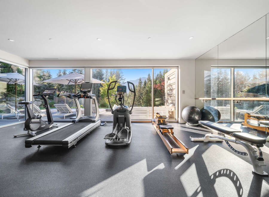 This modern home gym boasts a full suite of cardio equipment, including treadmills and an elliptical, perfect for your fitness routine.