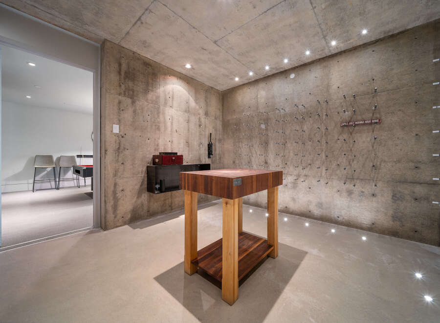 Discover a unique wine cellar with a rustic concrete aesthetic, featuring a prominent butcher block table as a centerpiece.