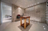 Discover a unique wine cellar with a rustic concrete aesthetic, featuring a prominent butcher block table as a centerpiece.