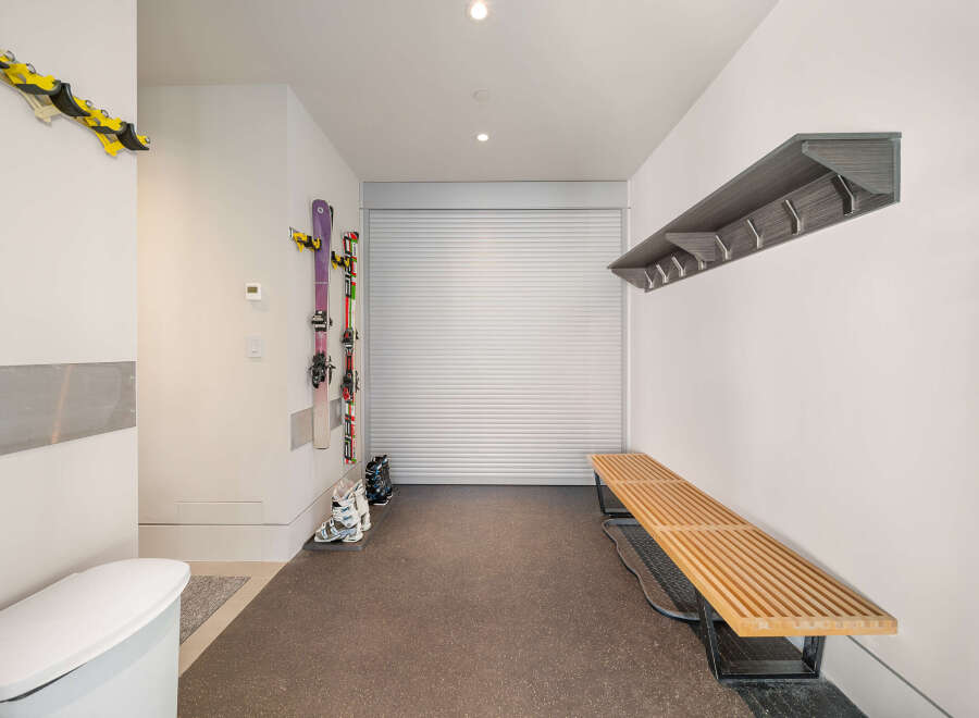 This spacious mudroom offers convenient storage solutions for your winter gear, featuring wall-mounted ski racks and a sleek coat rack.