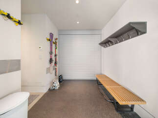 This spacious mudroom offers convenient storage solutions for your winter gear, featuring wall-mounted ski racks and a sleek coat rack.