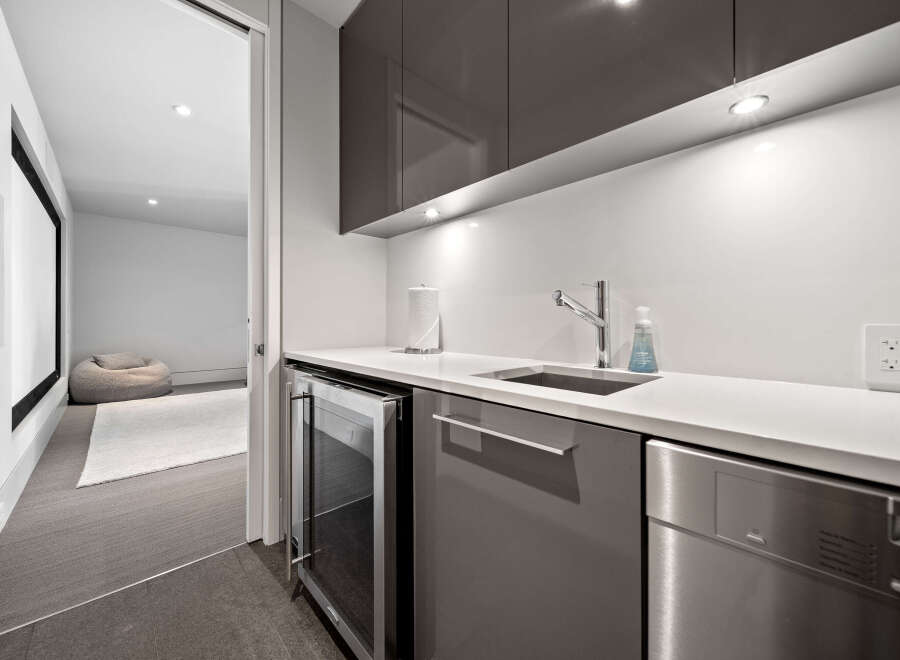 Discover modern living with this sleek wet bar, featuring a built-in wine fridge and stainless steel dishwasher.