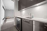 Discover modern living with this sleek wet bar, featuring a built-in wine fridge and stainless steel dishwasher.