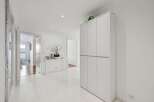 Step into this bright and airy hallway, featuring pristine white tiled floors that reflect the abundant natural light.