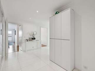 Step into this bright and airy hallway, featuring pristine white tiled floors that reflect the abundant natural light.
